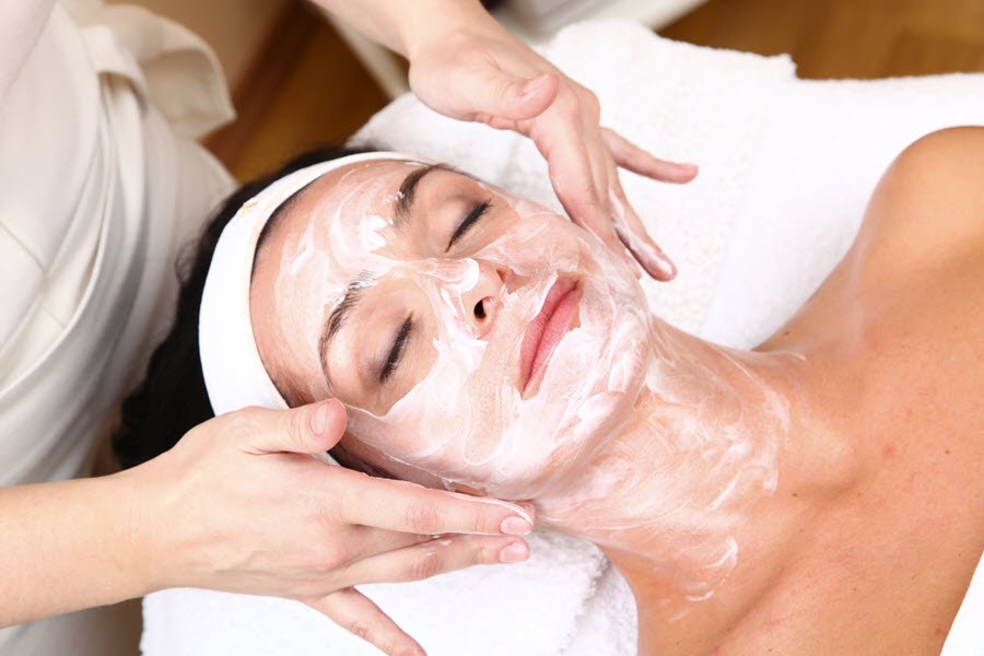 Esthetician massaging facial cream into a client’s face during a customized facial treatment.