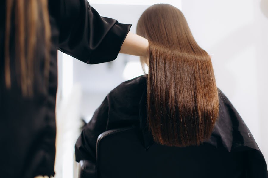 Close-up of smooth, straight brown hair being combed after a professional smoothing treatment.