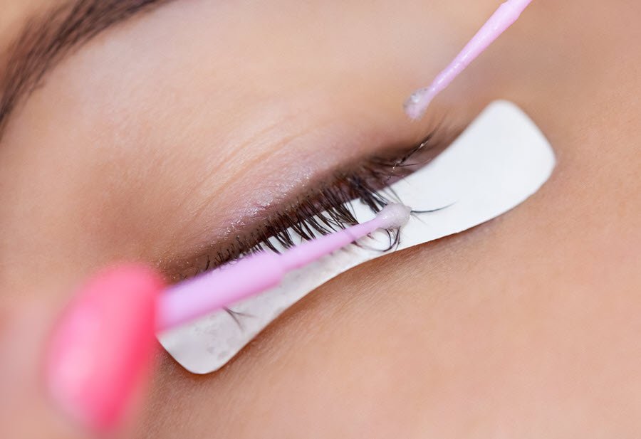 Lash technician working along a client’s lash line during a professional lash maintenance service.