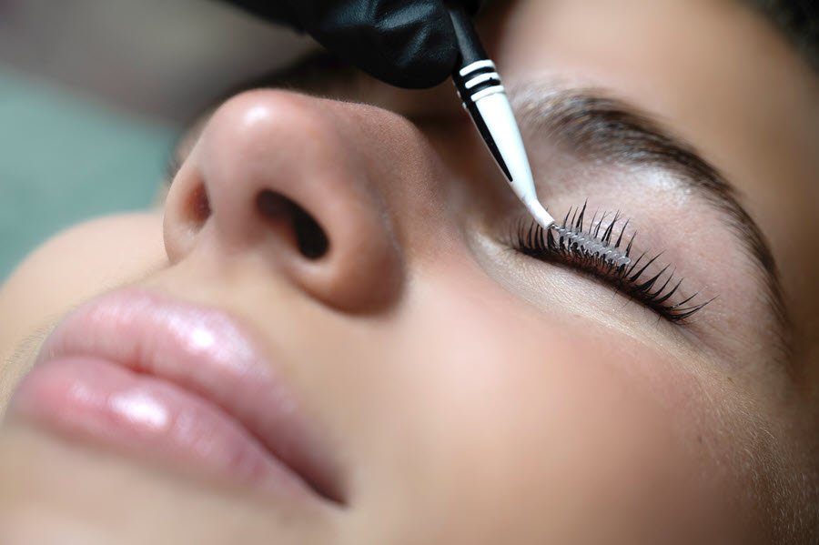Lash technician applying product to a client’s eyelashes during a lash lift and tint treatment.