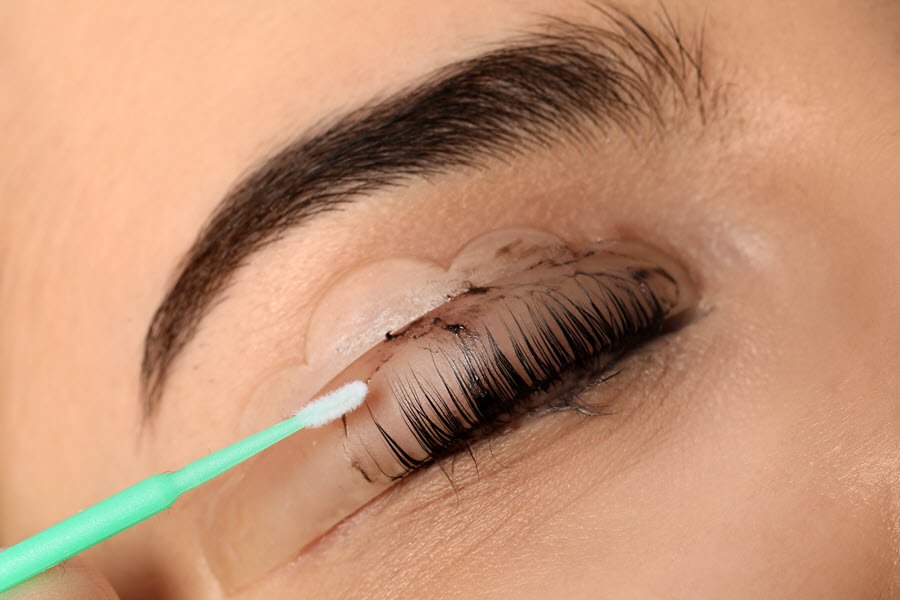 Lash technician applying product to a client’s natural eyelashes during a professional lash treatment.