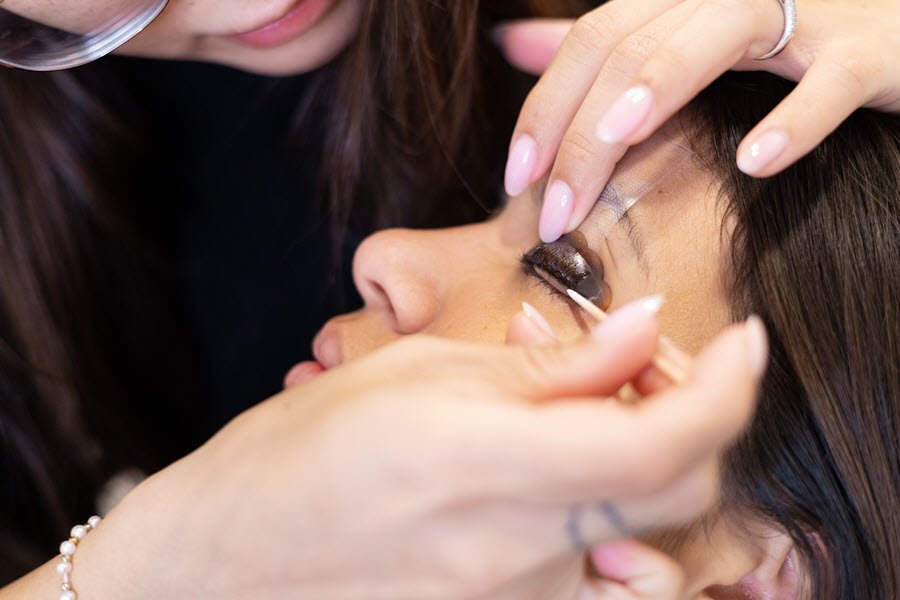 Lash artist applying individual false lashes to a client during a professional lash service.