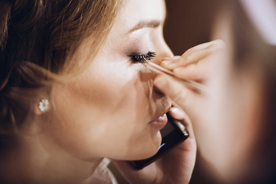 Beauty professional applying false lashes to a client during a makeup appointment.