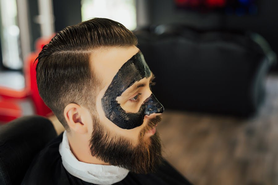 Male client receiving a facial mask treatment during a professional skin care service.