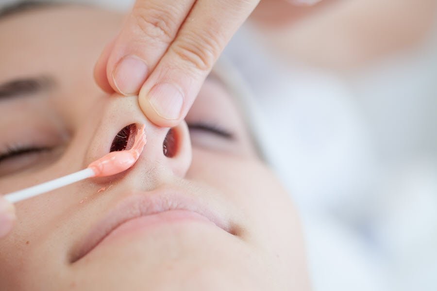 Beauty professional applying wax inside a client’s nostril during a nose waxing service.