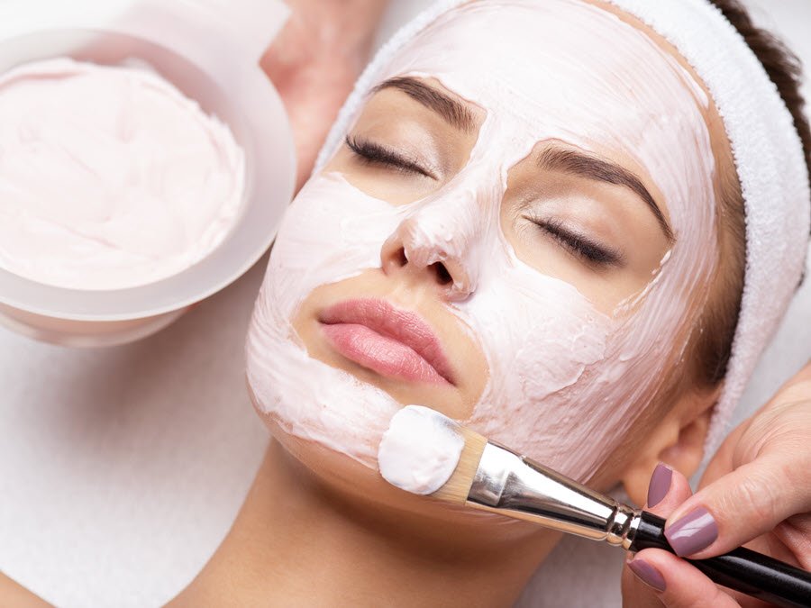 Esthetician applying a facial mask to a client during a professional skin care treatment.
