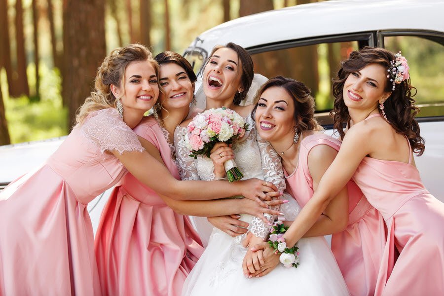 Bride standing with a group of bridesmaids dressed for a wedding celebration.